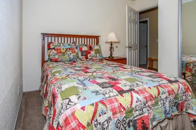 a bedroom with a bed with a colorful quilt at Ben's Cool Cabin - Phenomenal views and an ideal location close to all the local attractions! in Big Bear Lake