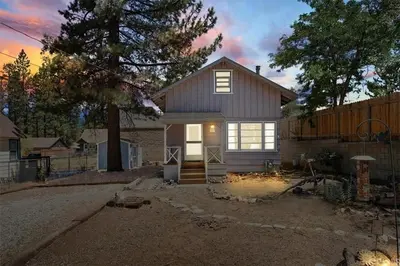 a small house in a yard with a fence at Big Bear Bungalow - Modern aesthetics meet mountain charm in this newly remodeled two-story home in Big Bear Lake