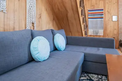 a blue couch with two blue pillows on it at Big Bear Bungalow - Modern aesthetics meet mountain charm in this newly remodeled two-story home in Big Bear Lake