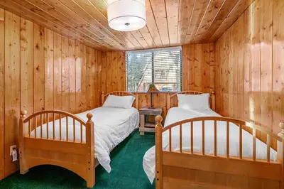 two beds in a room with wooden walls at Blue Lagoon - Classic Lakefront Cabin with Pool Table! in Big Bear Lake