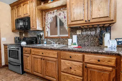 a kitchen with wooden cabinets and a sink and a stove at Boulder Bay Park Lakefront - Across the street from the lake and Boulder Bay Park! Hot tub! in Big Bear Lake