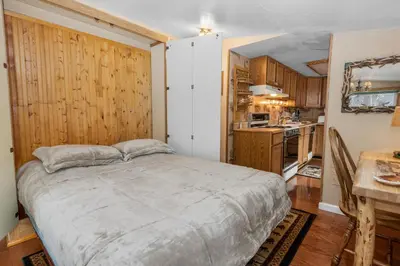 a bedroom with a large bed and a kitchen at Boulder Pines - Walk to lake and Boulder Bay park at those cozy location! in Big Bear Lake