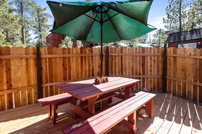 a picnic table with an umbrella on a wooden deck at Boulder Pines - Walk to lake and Boulder Bay park at those cozy location! in Big Bear Lake