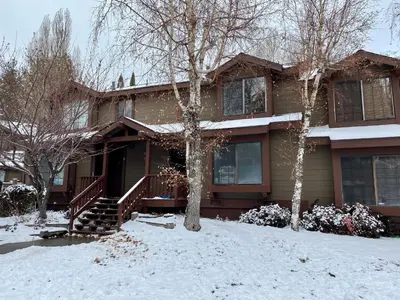 a house with snow on the ground in front of it at Brown Bear's Den - Spacious condo within walking distance to all Big Bear has to offer! in Big Bear Lake