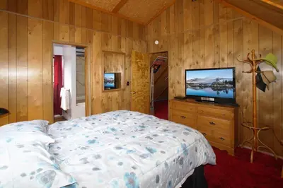 a bedroom with a bed and a flat screen tv at Canyon Cabin - A quaint cabin in a peaceful location yet close to Big Bear's attractions! in Fawnskin