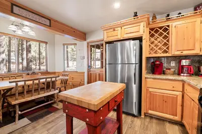 a kitchen with wooden cabinets and a stainless steel refrigerator at Catalina Creekside Cabin - Log home with wood burning fireplace for an immersive mountain getaway! in Big Bear Lake