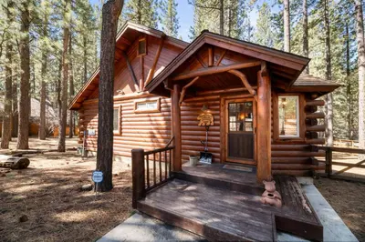 a log cabin in the woods with a door at Catalina Creekside Cabin - Log home with wood burning fireplace for an immersive mountain getaway! in Big Bear Lake