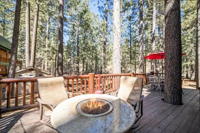a table and chairs on a deck with a fire pit at Catalina Creekside Cabin - Log home with wood burning fireplace for an immersive mountain getaway! in Big Bear Lake
