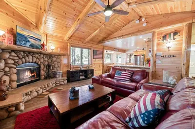 a living room with a couch and a fireplace at Catalina Creekside Cabin - Log home with wood burning fireplace for an immersive mountain getaway! in Big Bear Lake