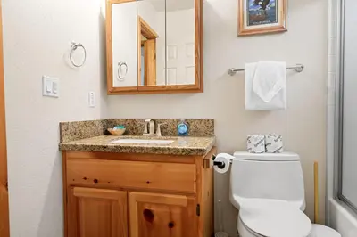 a bathroom with a toilet and a sink and a mirror at Catalina Creekside Cabin - Log home with wood burning fireplace for an immersive mountain getaway! in Big Bear Lake