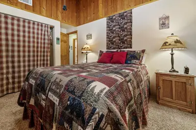 a bedroom with a bed and a lamp on a night stand at Catalina Retreat -Cozy mountain home in a tree filled neighborhood, plenty of games and a hot tub! in Big Bear Lake