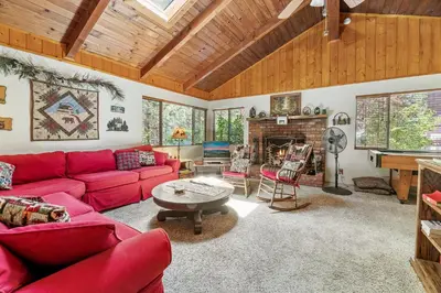 a living room with red couches and a fireplace at Catalina Retreat -Cozy mountain home in a tree filled neighborhood, plenty of games and a hot tub! in Big Bear Lake