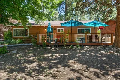 a house with two patio umbrellas in front of it at Catalina Retreat -Cozy mountain home in a tree filled neighborhood, plenty of games and a hot tub! in Big Bear Lake