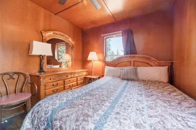 a bedroom with a bed and a chair and a mirror at Chalet Des Ours -Comfortable and spacious home with WIFI! Close to everything! in Big Bear Lake