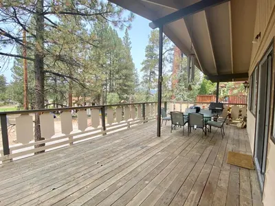 a porch with a table and chairs on a deck at Chalet Georgia - Spacious and cozy home, conveniently close to the heart of Big Bear! in Big Bear Lake