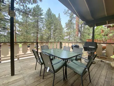 a table and chairs on a deck with a grill at Chalet Georgia - Spacious and cozy home, conveniently close to the heart of Big Bear! in Big Bear Lake