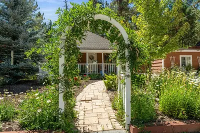 a garden with an archway in front of a house at Chipmunk House - Magical Boulder Bay cottage within a picturesque setting! in Big Bear Lake
