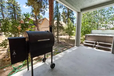 a grill on a screened in porch with a window at Cub Run Cabin - Spacious home close to the lake with Hot tub! in Big Bear Lake