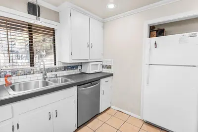 a kitchen with white cabinets and a sink and a refrigerator at Dream Street Escape -Private Hot Tub, near the Village and Lake! in Big Bear Lake