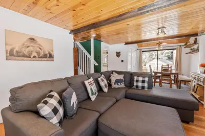 a living room with a brown couch with pillows at Dream Street Escape -Private Hot Tub, near the Village and Lake! in Big Bear Lake