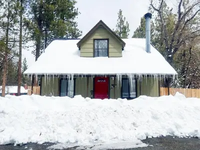 a house covered in snow next to a pile of snow at Dream Street Escape -Private Hot Tub, near the Village and Lake! in Big Bear Lake