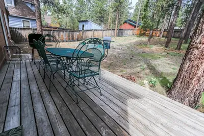 a patio with a table and chairs on a wooden deck at Eagle's Den - Cozy cabin with a beautiful wood burning fireplace! Foosball Table! in Big Bear Lake