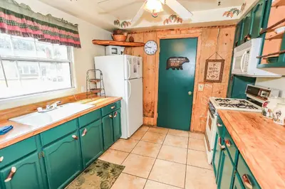 a kitchen with green cabinets and a white refrigerator at Eagle's Den - Cozy cabin with a beautiful wood burning fireplace! Foosball Table! in Big Bear Lake