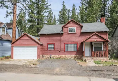 a red house with a white garage at Eagle's Den - Cozy cabin with a beautiful wood burning fireplace! Foosball Table! in Big Bear Lake