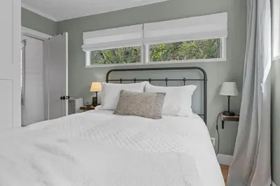 a bedroom with a white bed and two windows at Enchanted Hideaway - Newly remodeled with Hot Tub and Lake Views! in Fawnskin