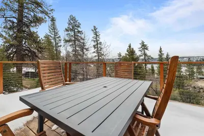 a wooden table and two chairs on a deck at Enchanted Hideaway - Newly remodeled with Hot Tub and Lake Views! in Fawnskin