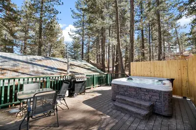 a hot tub on a deck with a table and chairs at Evergreen Paradise - Beautiful newly remodeled cabin with Hot Tub and Game Room! in Big Bear Lake