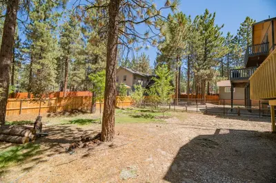 a yard with a tree and a fence at Fanciful Winter's Lake - Mix of old-world charm and modern-day gambrel style cabin! in Big Bear Lake