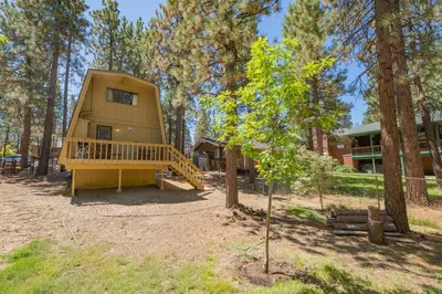 a tiny house in the woods with a tree at Fanciful Winter's Lake - Mix of old-world charm and modern-day gambrel style cabin! in Big Bear Lake