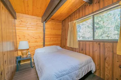 a bedroom with a bed in a wooden room at Fanciful Winter's Lake - Mix of old-world charm and modern-day gambrel style cabin! in Big Bear Lake