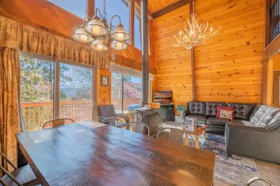 a dining room and living room with a large table at Fawnskin Family Cabin - Nicely decorated cabin with a lake view and a Foosball Table! in Fawnskin