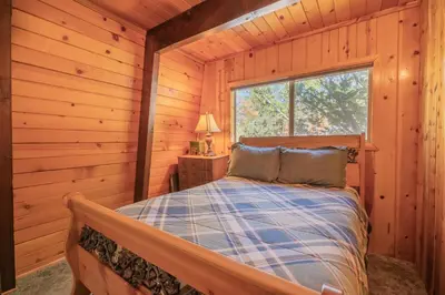 a bedroom with a bed in a log cabin at Fawnskin Family Cabin - Nicely decorated cabin with a lake view and a Foosball Table! in Fawnskin