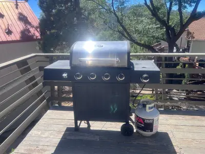 a blue barbecue grill with a bucket next to a fence at Fawnskin Family Cabin - Nicely decorated cabin with a lake view and a Foosball Table! in Fawnskin