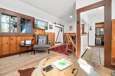 a living room with a table and a chair at Finns Fish Camp - Walking distance to Lake and Village! Back patio with barbecue, fully fenced yard! in Big Bear Lake