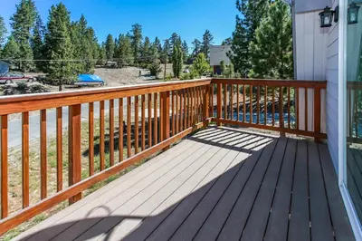 a wooden deck with a view of a yard at Five Pines - Beautifully remodeled gambrel cabin with Hot Tub and Fenced Yard! in Big Bear Lake