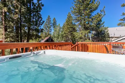 a hot tub on a deck with a wooden fence at Five Pines - Beautifully remodeled gambrel cabin with Hot Tub and Fenced Yard! in Big Bear Lake