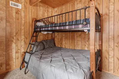 a bedroom with a bunk bed in a cabin at Forest Edge Retreat - Cozy, log cabin with a wood burning fireplace! Pool Table, Foosball and Darts! in Big Bear City