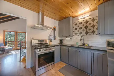 a kitchen with gray cabinets and a stove top oven at Forest Escape - Situated on the quiet side of the lake, nicely decorated contemporary cabin! in Fawnskin