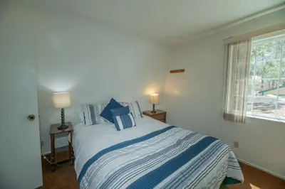 a bedroom with a bed with a blue and white striped blanket at Glenview Getaway - Cozy farm house! Walking distance to the lake! in Big Bear Lake