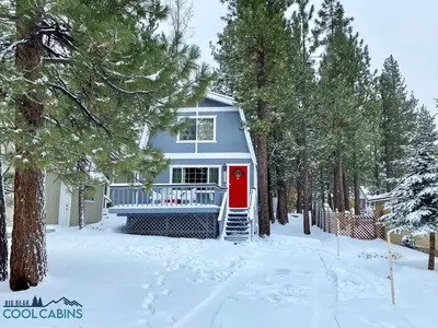 a blue house with a red door in the snow at Glenview Getaway - Cozy farm house! Walking distance to the lake! in Big Bear Lake