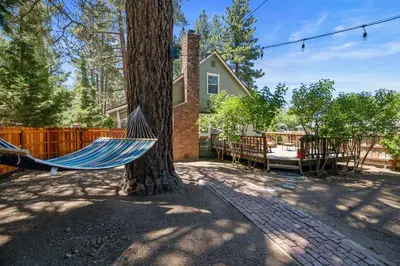 a hammock hanging from a tree in front of a house at Happy Hours - Modern Cabin with Game Room and Peek-a-Boo Lake Views! in Big Bear Lake