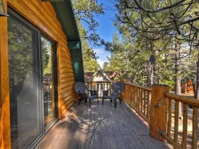 a porch of a wooden house with a table and chairs at Ivvy Bear Lodge - Charming log cabin with Hot tub! Short walk to Village! in Big Bear Lake