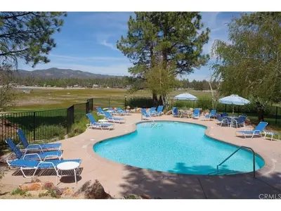 a swimming pool with lounge chairs and a bunch ofitures at Junipine Lakefront Condo - Walking distance to the lake! Less than 2 miles from the slopes! in Big Bear Lake