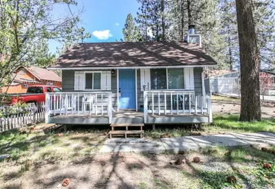 a small white house with a blue door at Knotty Knight- Walking distance to the lake as well as the Village! in Big Bear Lake