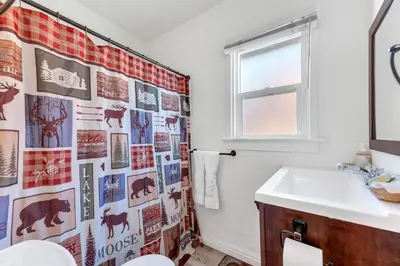 a bathroom with a sink and a shower curtain at Lakefront Oasis - Adorable lakefront cabin with a private beach! in Big Bear Lake