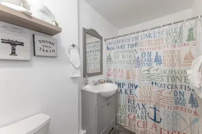 a white bathroom with a sink and a mirror at Lakefront Oasis - Adorable lakefront cabin with a private beach! in Big Bear Lake